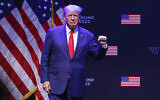 Former US President Donald Trump raises his fist as he arrives on stage to speak about education policy at the Adler Theatre in Davenport, Iowa on March 13, 2023. (Kamil Krzaczynski/AFP)