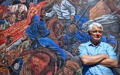 Veteran journalist John Ware in front of the mural at Cable Street depicting the famous 'battle' that took place there in 1936 against Oswald Mosley’s fascists as they marched through the heavily-Jewish East End of London. (Courtesy)