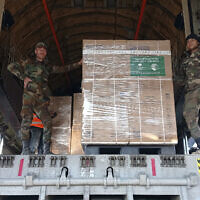 In this photo released by the official Syrian state news agency SANA, Syrian soldiers unload humanitarian aid sent from Saudi Arabia following a devastating earthquake, at the airport in Aleppo, Syria, Tuesday, Feb. 14, 2023. (SANA via AP)