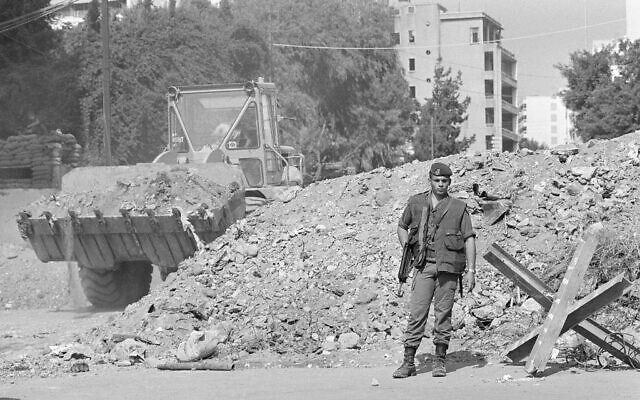 FILE - While a French trooper stands guard, an earth mover constructs a block of a street to beef up security near French paratroop command two days after it was attacked by a terrorist bomb, in Beirut, October 25, 1983. (AP Photo/Azakir, File)