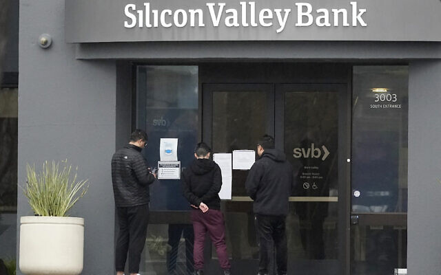 People look at signs posted outside of an entrance to Silicon Valley Bank in Santa Clara, California, March 10, 2023. (Jeff Chiu/AP)