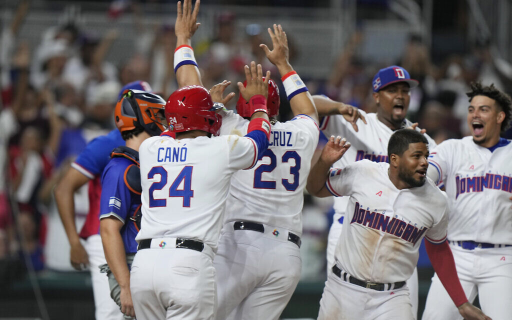 Dominican Republic players celebrate with Robinson Cano (24) and Nelson Cruz (23) after Jean Segura hit a ground rule double scoring Cano and Cruz for a mercy rule 10-0 win in the seventh inning of a World Baseball Classic game against Israel, Tuesday, March 14, 2023, in Miami. (AP/Wilfredo Lee)