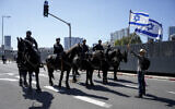 Mounted policemen block a protestor against plans by Prime Minister Benjamin Netanyahu's government to overhaul the judicial system from approaching to the main freeway in Tel Aviv, Israel, March 16, 2023. (AP Photo/Oded Balilty)