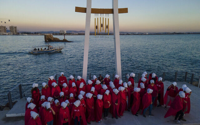 Protesters supporting women's rights dressed as characters from The Handmaid's Tale TV series attend a protest against plans by Prime Minister Benjamin Netanyahu's new government to overhaul the judicial system in the old port of Acre, north Israel, Thursday, March 16, 2023. (AP Photo/Ariel Schalit)