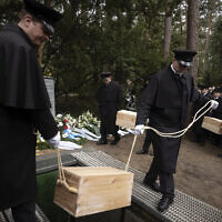Caskets containing bones found on the grounds of the Freie Universitat, Free University are lowered into the ground for burial, at the Waldfriedhof in Berlin, Germany, Thursday, March 23, 2023. (AP Photo/Markus Schreiber)