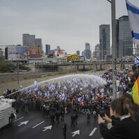 Police use a water cannon to disperse demonstrators blocking the freeway during a protest against plans by Prime Minister Benjamin Netanyahu's government to overhaul the judicial system in Tel Aviv, Israel, March 23, 2023. (AP Photo/Oded Balilty)