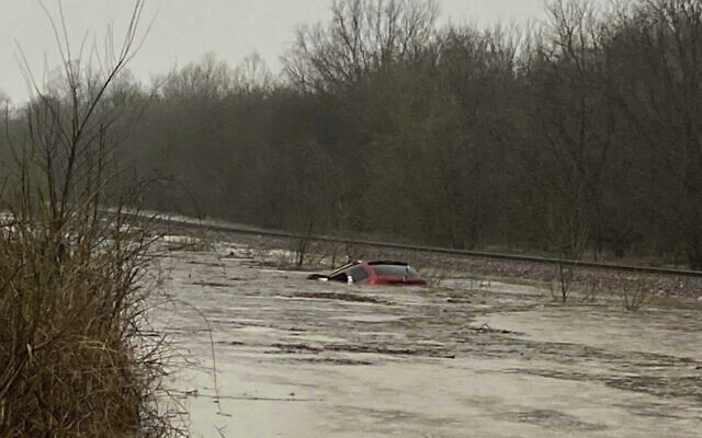 In this photo provided by Layton Hoyer, a red SUV is seen submerged in floodwater on Old Ritchey Road in Granby, Mssouri, March 24, 2023. Hoyer rescued an elderly woman from the car. (Layton Hoyer via AP)