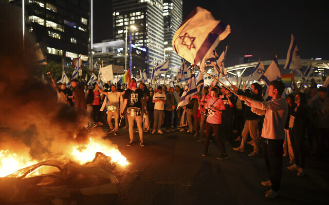 Israelis opposed to Prime Minister Benjamin Netanyahu's judicial overhaul plan set up bonfires and block a highway during a protest moments after he fired Defense Minister Yoav Gallant, in Tel Aviv, March 26, 2023. (AP Photo/Oren Ziv)
