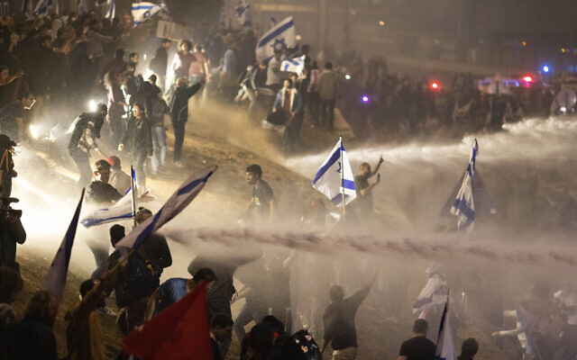 Police use a water cannon to disperse demonstrators blocking a highway during a protest against plans by Prime Minister Benjamin Netanyahu's government to overhaul the judicial system, in Tel Aviv, Israel, Monday, March 27, 2023. (AP Photo/Oren Ziv)