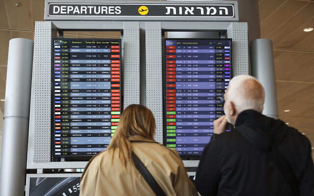 Passengers look at a monitor displaying delayed flights at Ben Gurion airport, March 27, 2023. (AP Photo/Oren Ziv)