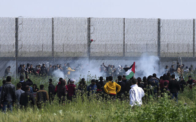 Palestinians try to destroy the fence while Israeli troops shot teargas during clashes along Gaza's border fence with Israel, east of Gaza City, March 30, 2023. (AP Photo/Adel Hana)