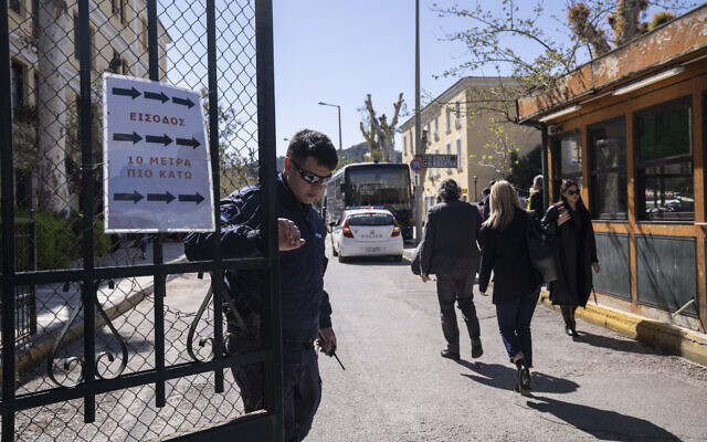 A Greek police officer closes the entrance of the court house following the transfer of suspects that have been charged with membership in a terrorist organization, in Athens, March 2023. (AP Photo/Petros Giannakouris)