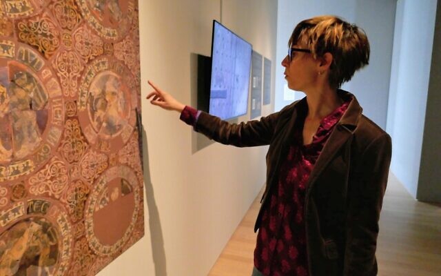 College of the Holy Cross visual arts professor Amanda Luyster, guest curator of the new exhibit 'Bringing the Holy Land Home,' shows a reconstructed conception of a floor design at Chertsey Abbey, England, bearing images of the Crusades, in Worcester, Massachusetts, on March 8, 2023. (Photo / Laura C. Arena)