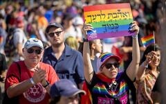 A woman at the annual Gay Pride Parade in Jerusalem, on June 2, 2022, holds up a sign with the biblical phrase 'Love thy neighbor as thyself.' (Yonatan Sindel/Flash90)