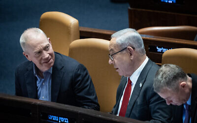Defense Minister Yoav Gallant, left, speaks with Prime Minister Benjamin Netanyahu during a vote in the Knesset plenum in Jerusalem, February 15, 2023. (Yonatan Sindel/Flash90)