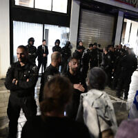 Police officers stand guard while people demonstrate against the prime minister's wife Sara Netanyahu, outside a hair salon in Tel Aviv on March 1, 2023. (Avshalom Sassoni/Flash90)