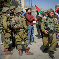 Palestinians confront Israeli soldiers while waving Palestinian flags in the center of the town of Huwara, in the West Bank, March 2, 2023. (Nasser Ishtayeh/Flash90)