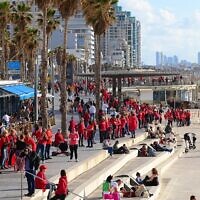 Hundreds of women dressed in red mark International Women's Day and demonstrate against the government's planned judicial overhaul, on the beach in Tel Aviv, March 8, 2023. (Tomer Neuberg/Flash90)