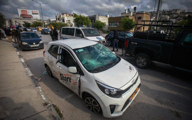 Palestinian police stand next to an Israeli ride-sharing car driven by German tourists that was attacked by Palestinians in the West Bank city of Nablus, March 18, 2023. (Nasser Ishtayeh/Flash90)