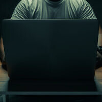 Illustrative: A man sits with a laptop in a dark room (tanawit sabprasan; iStock by Getty Images)