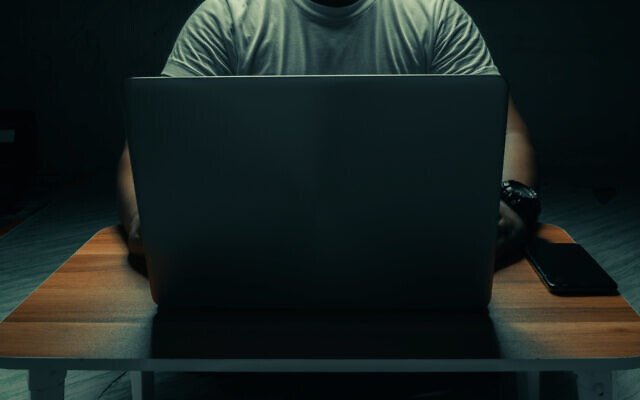 Illustrative: A man sits with a laptop in a dark room (tanawit sabprasan; iStock by Getty Images)