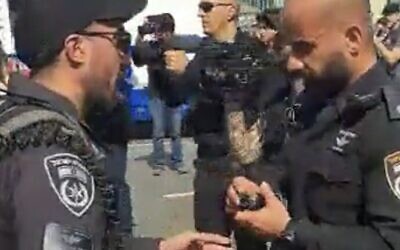 A police officer, right, prepares a stun grenade moments before he hurled it into a crowd of demonstrators during a mass protest in Tel Aviv, March 1, 2023 (Video screenshot; Used in accordance with Clause 27a of the Copyright Law)