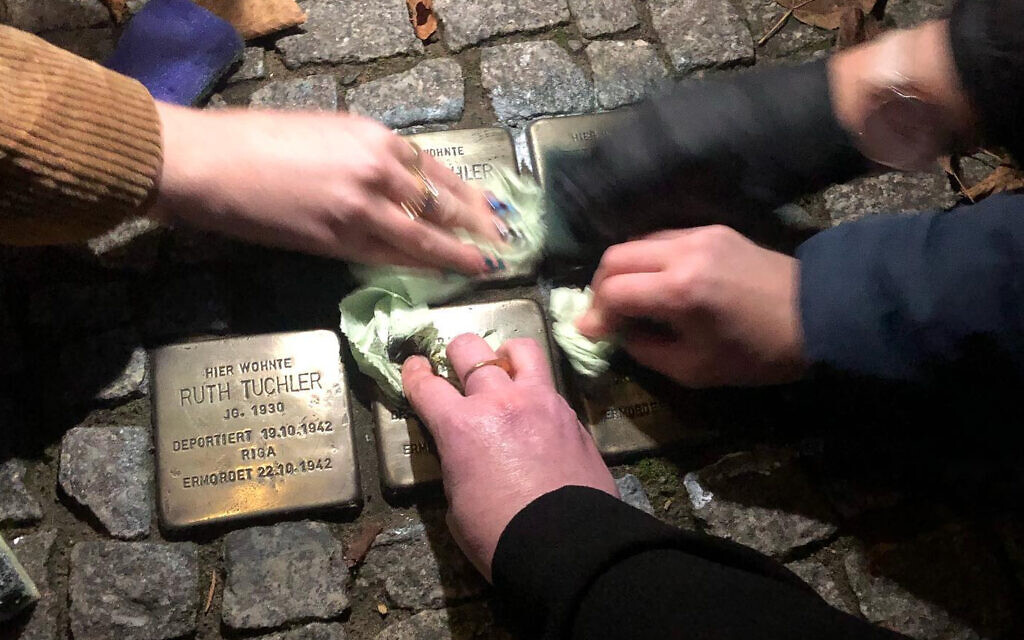 German and 'Zikaron BaSalon' volunteers clean Stolpersteine (stumbling stones) in commemoration of Kristallnacht, November 11, 2022. (Courtesy of MakeTheirMemoryShine)