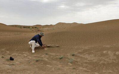 Archaeologist Aqeel Mansarawi searches for the remains of an ancient structure at the Umm al-Aqarib archaeological site, frequently buried by sandstorms due to desertification, in the district of al-Rifai in Iraq's southern Dhi Qar province, March 31, 2023. (Asaad NIAZI/AFP)