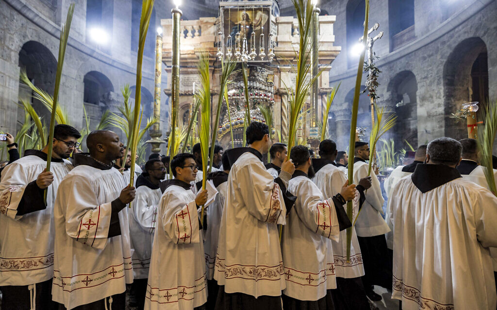 Roman Catholic deacons walk with palm fronds as they circle in a procession around the Edicule, traditionally believed to be the burial site of Jesus Christ, at the Church of the Holy Sepulchre in Jerusalem on April 2, 2023, Palm Sunday according to Catholic Christians. (MENAHEM KAHANA / AFP)