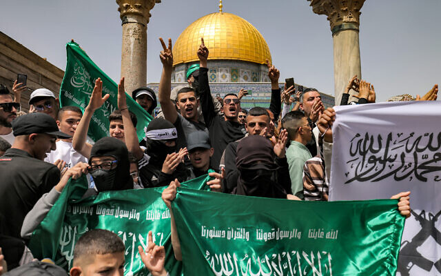 Palestinian Hamas supporters chant slogans and flash gestures with flags of the terror group outside the Dome of the Rock shrine at the Temple Mount compound in the Old City of Jerusalem on April 7, 2023. (Ahmad Gharabli/AFP)