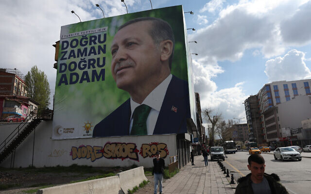 Pedestrians walk past billboards showing the portrait of Turkish President Tayyip Erdogan and a slogan reading "For Turkey's century; the right time, the right man," on a building in Ankara ahead of the May 14 presidential and parliamentary elections, on April 20, 2023. (Adem Altan/AFP)