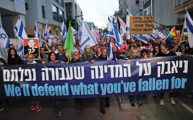 Demonstrators lift a banner during a rally to protest the Israeli government's judicial overhaul bill in Tel Aviv, on April 22, 2023. (Jack Guez/AFP)
