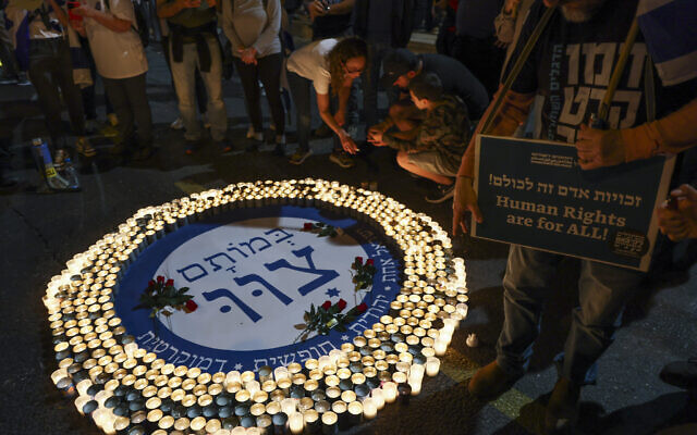 Demonstrators light memorial candles during a rally to protest the government's judicial overhaul plans, in Tel Aviv, on April 22, 2023, three days before Israel's annual memorial day for fallen soldiers. The text reads: "In their deaths, they commanded us: One Israel. Jewish. Free. Democratic" (Photo by JACK GUEZ / AFP)