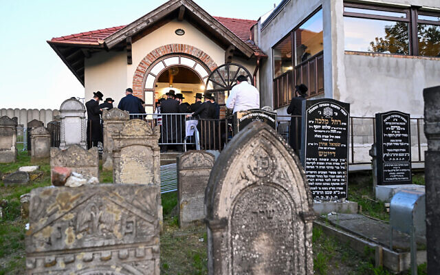 Hasidic Jewish pilgrims pray outside the tomb of late miracle rabbi Yeshaya Steiner, also known as Rebbe Shaya'le, at the Jewish cemetery in the village of Bodrogkeresztur, Hungary, on April 23, 2023, during a pilgrimage of Hasidic Jews on the occasion of Rabbi Steiner's 98th death anniversary. (ATTILA KISBENEDEK/AFP)