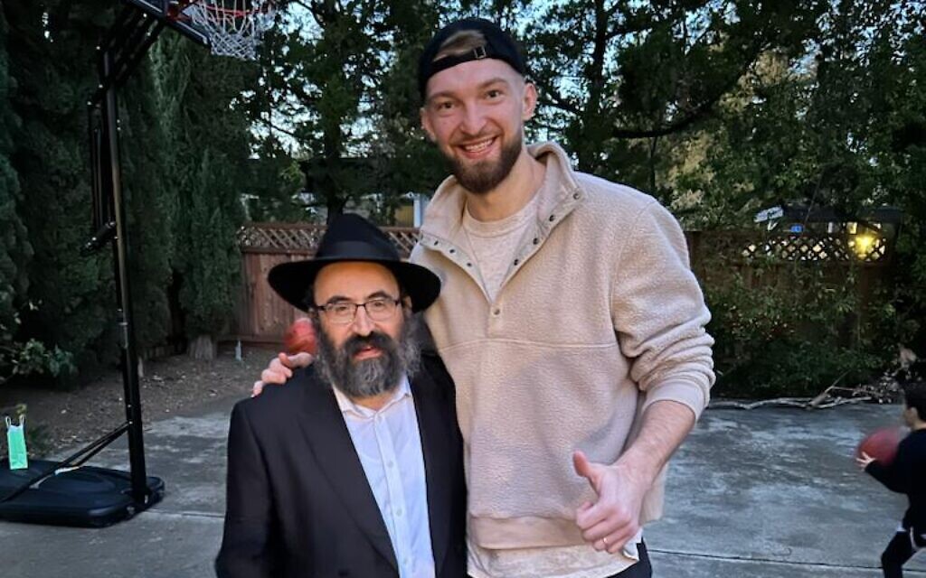 Rabbi Mendy Cohen is dwarfed by 7-foot-1 Kings center Domantas Sabonis, who attended Chabad of Sacramento's Purim party on March 7. (Courtesy of Chabad of Sacramento via JTA)