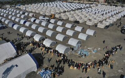 People who lost their houses in the devastating earthquake, lineup to receive aid supplies at a makeshift camp, in Iskenderun city, southern Turkey, February 14, 2023. (Hussein Malla/AP)