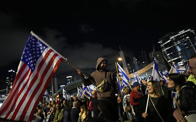A protester holds an American flag at a rally against the Israeli government's plan to overhaul the judicial system, in Tel Aviv, Israel, Saturday, April 1, 2023. (AP Photo/Ohad Zwigenberg)