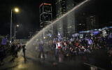 Police deploy a water cannon on people occupying the Ayalon Highway to protest government plans to overhaul the judicial system, in Tel Aviv, Saturday, April 1, 2023. (AP Photo/Ohad Zwigenberg)
