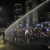 Police deploy a water cannon on people occupying the Ayalon Highway to protest government plans to overhaul the judicial system, in Tel Aviv, Saturday, April 1, 2023. (AP Photo/Ohad Zwigenberg)