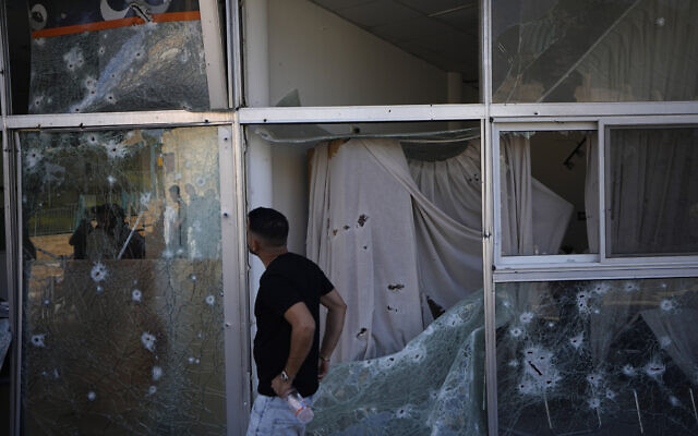A man inspects damage to a bank from a rocket fired from Lebanon in Shlomi, northern Israel, April 6, 2023. The branch was closed for Passover. (AP Photo/Ariel Schalit)
