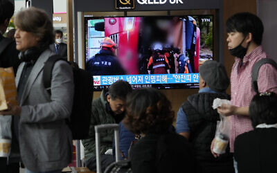 A TV screen shows an image of an overturned tour bus during a news program at the Seoul Railway Station in Seoul, South Korea, April 14, 2023. (AP Photo/Ahn Young-joon)