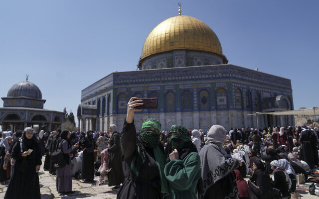 A pair of Muslim women worshippers, one wearing a headband in support of Hamas' military wing, the Qassam Brigades, take a photo as they gather for Friday prayers next to the Dome of Rock at the Al-Aqsa Mosque compound in the Old City of Jerusalem during the Muslim holy month of Ramadan, Friday, April 14, 2023. (AP Photo/Mahmoud Illean)
