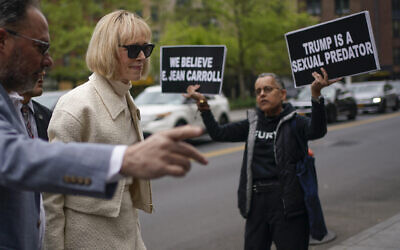While a protester holds up signs, E. Jean Carroll arrives to federal court in New York, April 27, 2023. (AP Photo/Seth Wenig)