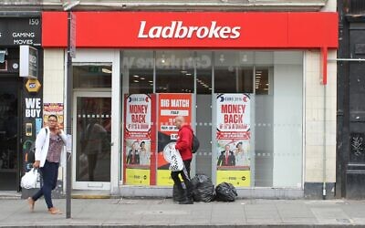 People walk past a Ladbrokes betting shop in London, Wednesday June 22, 2016. (AP Photo/Leonora Beck)