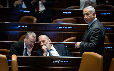 Shas leader Aryeh Deri (C) confers with Justice Minister Yariv Levin (L) as Prime Minister Benjamin Netanyahu looks on during a vote in the Knesset in Jerusalem, on March 27, 2023. (Yonatan Sindel/Flash90)