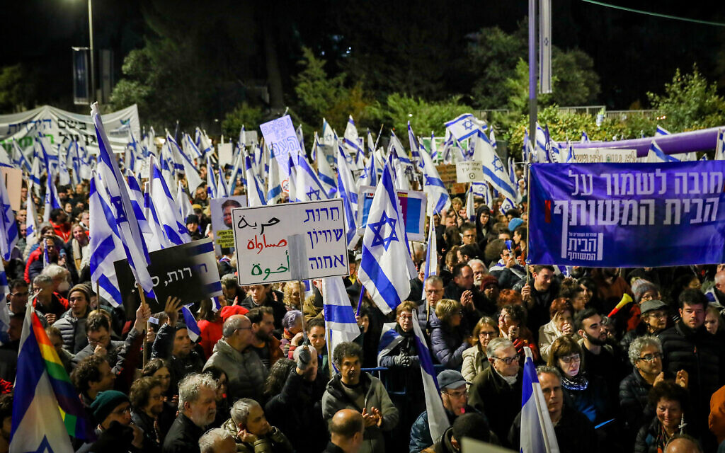 Israelis protest against the government's planned judicial overhaul, outside the President's Residence in Jerusalem, on April 1, 2023. The banner at right reads: "It's vital to safeguard the common home"; the banner at center reads: "Freedom, equality, kinship." (Noam Revkin Fenton/Flash90)