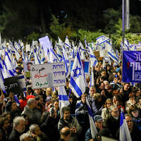 Israelis protest against the government's planned judicial overhaul, outside the President's Residence in Jerusalem, on April 1, 2023. The banner at right reads: "It's vital to safeguard the common home"; the banner at center reads: "Freedom, equality, kinship." (Noam Revkin Fenton/Flash90)