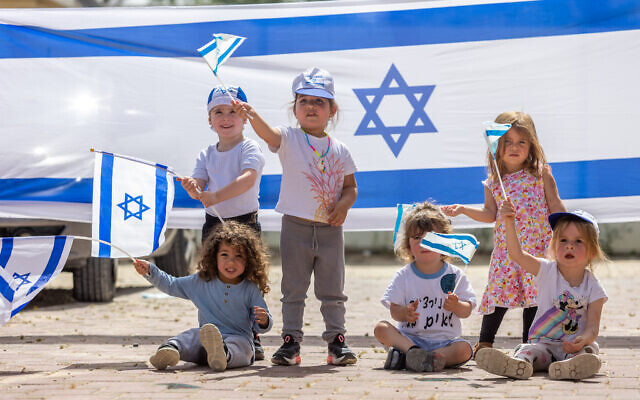 Children play with Israeli flags ahead of Israel's 75th Independence Day in Moshav Yashresh, on April 19, 2023 (Yossi Aloni/Flash90)