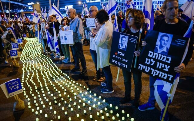 Bereaved families and other Israelis stand next to memorial candles during a protest against the Israeli government's planned judicial overhaul, in Tel Aviv on April 22, 2023. (Erik Marmor/Flash90)