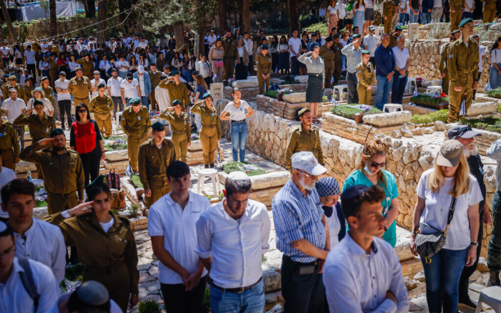 Israelis stand in silence next to graves of soldiers at the Mount Herzl miitary cemetery in Jerusalem during the Memorial Day siren, April 25, 2023. (Erik Marmor/Flash90)